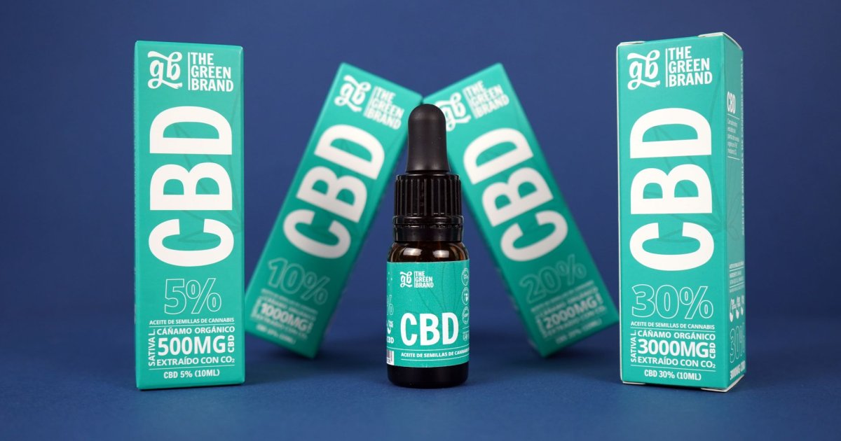 Flacone di olio di CBD con contagocce accanto a fiori di camomilla su un tavolo di legno, che evoca relax e sonno naturale