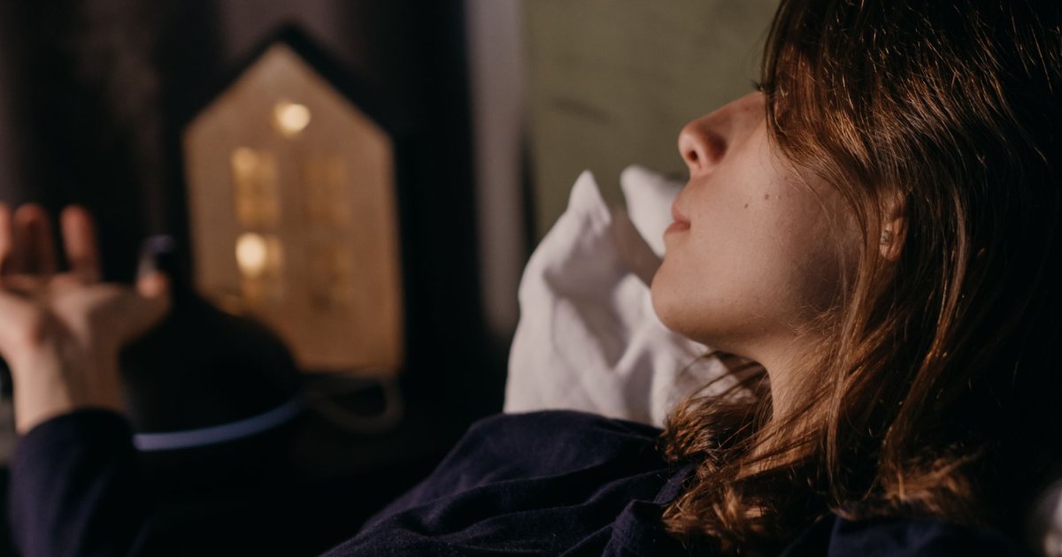 Una persona distesa a letto che pratica la respirazione diaframmatica per addormentarsi in modo naturale e rilassato