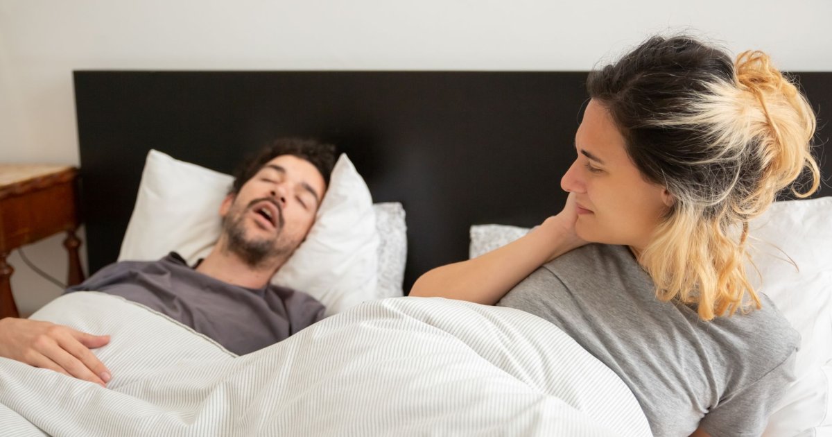 Uomo che dorme nel letto mostrando segni di sonno disturbato e possibile apnea notturna